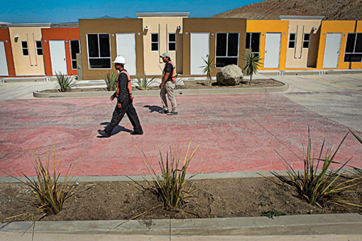 Workers in Tijuana, Mexico walk past newly constructed homes in the Valle de las Palmas residential project. Photo: David Maung/Bloomberg/Getty