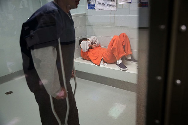 Immigrants wait in a processing cell at the Adelanto Detention Facility