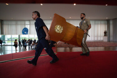 Workers carry a lectern inside Brazil's presidential palace, preparing for the two-minute speech given by President Bolsonaro after his defeat in the October 30 election.