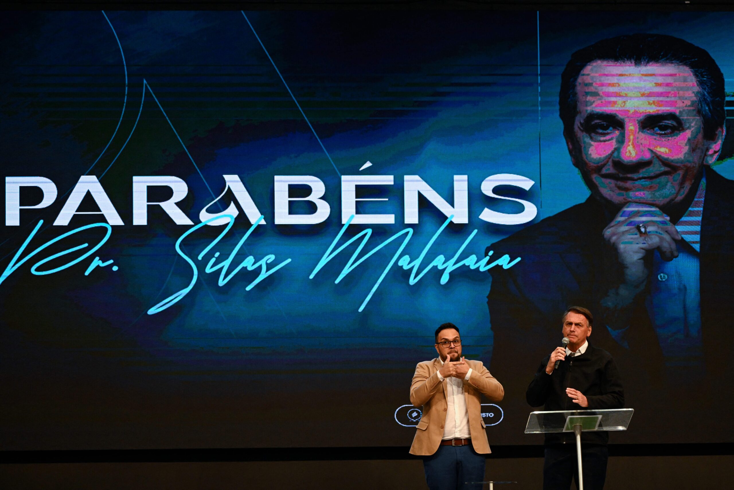 A Brazilian evangelical megachurch pastor and former President Jair Bolsonaro of Brazil stand together on stage.