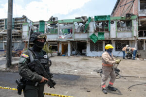 A member of the Colombian National Police's Special Operations Group stands guard as cleaners clear debris from the site of a bomb explosion in Cali, Colombia in August.