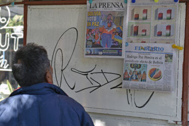 A passer-by looks at morning papers' front page showing the results of the presidential election runoff, in La Paz, on October 20, 2025. Bolivians on the eve elected pro-business center-right senator Rodrigo Paz as their new president, ending two decades of socialist rule that have left the South American nation deep in economic crisis. (Photo by Jorge BERNAL / AFP) (Photo by JORGE BERNAL/AFP via Getty Images)
