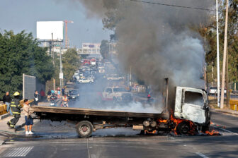 Firefighters extinguish a burning truck set on fire by organized crime groups in Guadalajara, Mexico, on Feb. 22